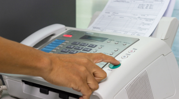 A person sending a document using a fax machine